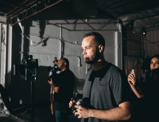 Two men and a woman working as part of a film crew, with one man watching a monitor.